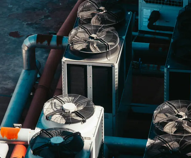 A row of air conditioning condensers on a wall